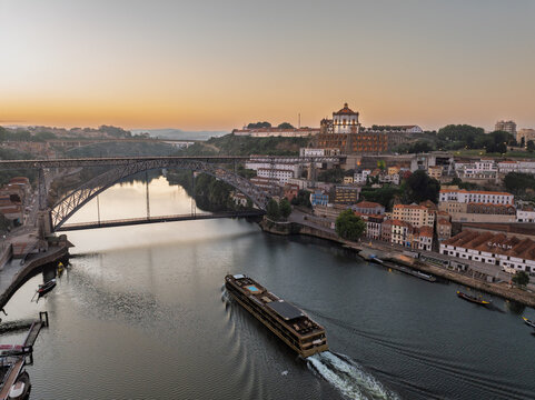 Cruise Ship in Sunrise Light Dom Luis Bridge in Porto City, Portogal. Drone. Douro River. Monastery in Background