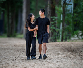 Obraz premium Young 20's Chinese Asian Couple Smiling While Enjoying a Walk Through the Forest Park