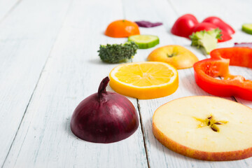 sliced fruit and vegetable circles on white wood table