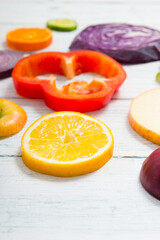 sliced fruit and vegetable circles on white wood table