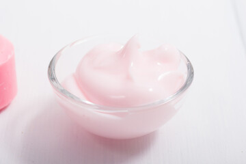 cosmetic cream, soap and bath salt with pink flower, white wood table