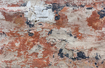Abstract texture of a weathered wall with peeling paint in shades of brown, red, and white.