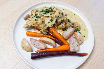 A plate of chicken with mushroom sauce and root vegetables.