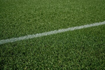 Patterned illumination and shade on the turf of a football pitch.