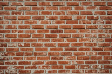 Obraz premium Textured red brick wall featuring worn bricks and cement seams with a rustic, distressed look, perfect for vintage, urban, or architectural design work.