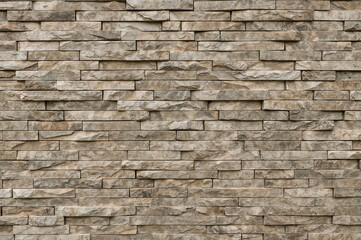 Obraz premium Exterior wall adorned with layered natural multicolored stone bricks, showcasing a striped pattern.