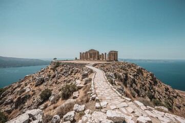 Ancient city ruins atop a plateau on a volcanic island, featuring vintage architecture and scenic mountain and sea views