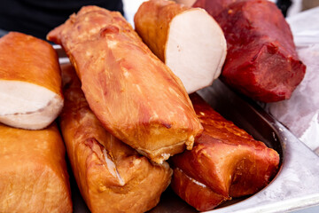 Smoked meats displayed on a market stall showcasing a variety of textures and colors in a bustling outdoor environment during a local food festival