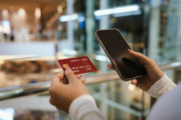 A beautiful young woman smiles while paying with a credit card at a café, embracing online shopping, finance, technology, and lifestyle.