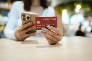 A beautiful young woman smiles while paying with a credit card at a café, embracing online shopping, finance, technology, and lifestyle.
