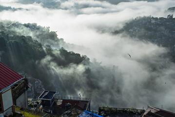 Dramatic fog and mist in a morning sun ray cityscape over hill city of Aizawl