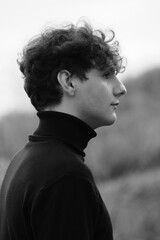 Portrait of a guy in black clothes. Curly dark hair