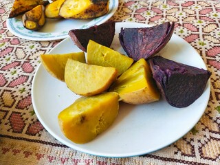 Steamed white sweet potatoes, steamed purple sweet potatoes, and steamed bananas are served as a...