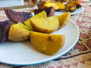 Steamed white sweet potatoes, steamed purple sweet potatoes, and steamed bananas are served as a...