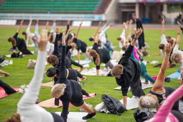 Group yoga session on stadium lawn in FYSM style