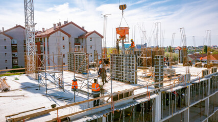 Aerial view on masons fill up vertical mold with help of crane as carry cone tank for cement mixture © Roman_23203