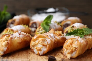 Delicious cannoli with cheese, nuts, powdered sugar and mint on table, closeup