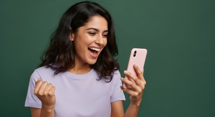 Woman with dark hair and light purple shirt looking at pink phone with excited expression on green background