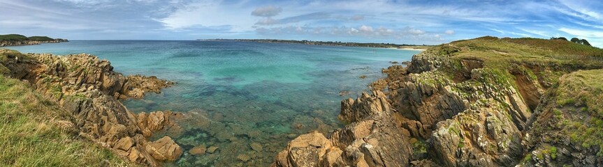 A scenic coastal panorama featuring rocky cliffs and clear turquoise waters