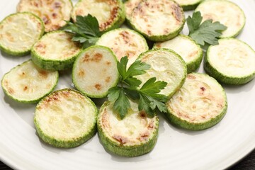 Delicious fried courgette slices with parsley on plate, closeup