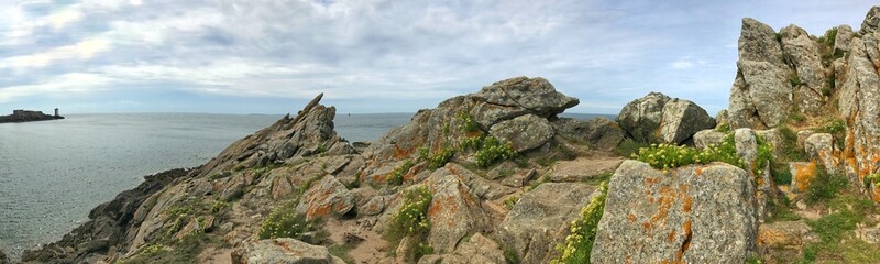 Rocky coastline panorama with ocean view and distant lighthouse