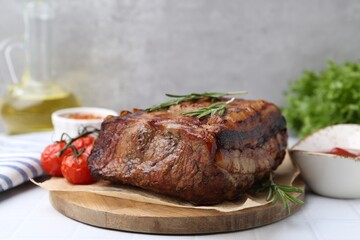 Delicious roast beef with rosemary and tomatoes on light table, closeup