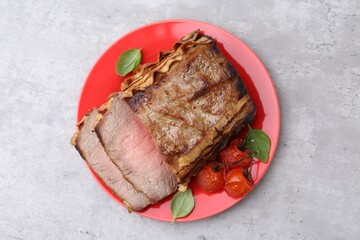 Delicious baked beef meat, tomatoes and basil on grey table, top view