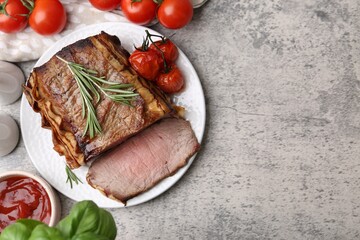 Delicious baked beef meat, tomatoes, basil, rosemary and sauce on grey table, flat lay. Space for text