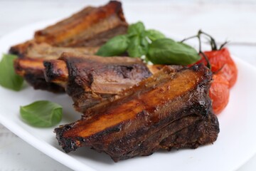 Roasted beef ribs, tomatoes and basil on table, closeup