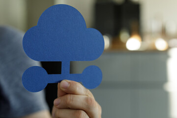 Person holding a blue paper cloud network symbol.  Illustrates cloud storage, data sharing, and...