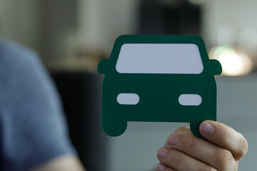 Close-up of a hand holding a green paper car cutout.  Concept for auto insurance, buying a car, or transportation.