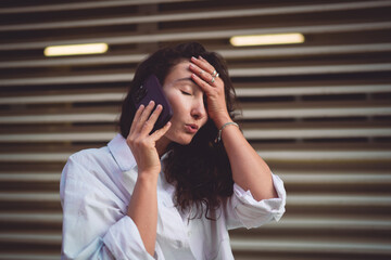 Frustrated woman holds smartphone during a call, showing stress. Conceptual image symbolizing the...