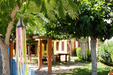 Vibrant ribbons adorn trees in a tranquil garden setting. Perfect for summer, nature, and tranquility themes.