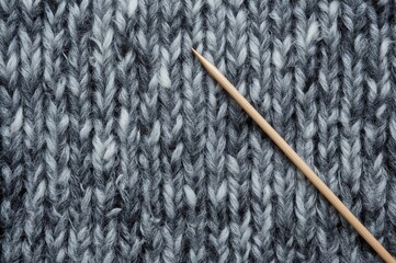 Cozy grey melange sweater crafted with knitting needles. Blend of wool and cashmere fibers. Background featuring knitting patterns. Knitting as a relaxing pastime. Warm handmade garment. Expert