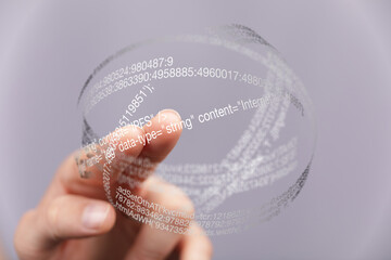 Close-up of finger interacting with a transparent sphere showing digital data and code.