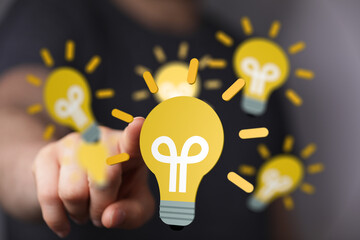 Hand choosing a lightbulb, symbolizing idea selection, innovation, and solutions.