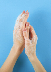 Fototapeta premium girl washes her hands with soap, hygiene and cleanliness of hands. Vertical photo format