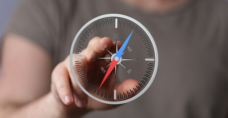 Close-up of hand interacting with a digital compass on a screen, showing navigation and direction.