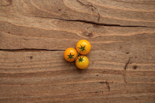 Small yellow cherry tomato on a rustic wooden surface