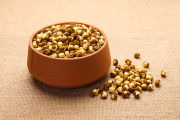 Indian food called roasted Chickpeas or Roasted Chana in mud pot isolated on jute background 