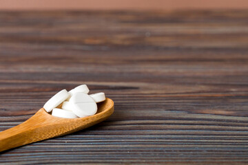 Heap of white pills on colored background. Tablets scattered on a table. Pile of red soft gelatin capsule. Vitamins and dietary supplements concept
