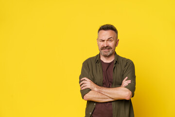 A man with a prominent mustache stands confidently in a green shirt, arms crossed, in front of a...