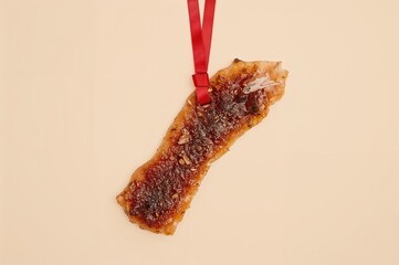 Dried meat hanging on a string with spices and a bow on a neutral backdrop