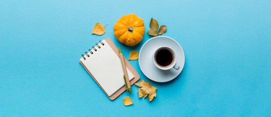 Autumn composition: fallen leaves and notebook mock up on colored background. Top view. Flat lay...