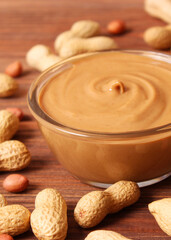 creamy peanut butter and peanuts beans on wooden background top view. Vertical photo format
