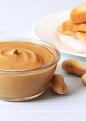 creamy peanut butter and peanuts beans on wooden background top view. Vertical photo format