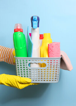 A set of cleaning products in female hands on a colored background. Vertical photo format