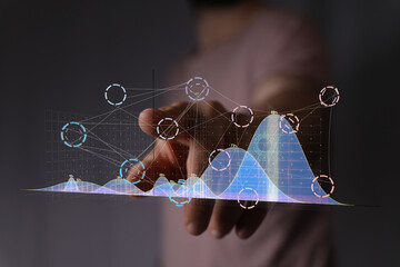 Hand pointing at futuristic holographic graphs, data analysis concept.