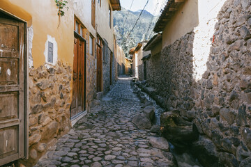 Traditional narrow alleyway with ancient Inca stone walls and cobblestone pavement in the historic town of Ollantaytambo, Peru.