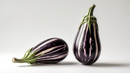 Uncooked striped eggplants placed against a white backdrop